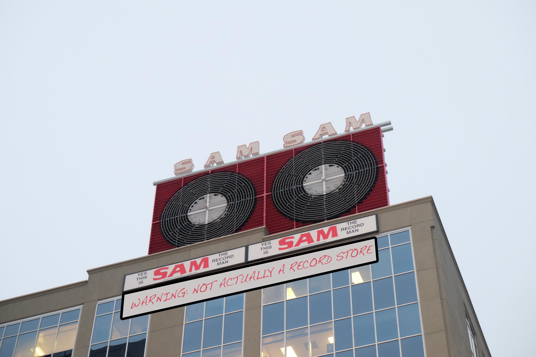 Pictured here, the Sam the Record Man Sign with a handwritten sign underneath that reads, warning: not actually a record store.