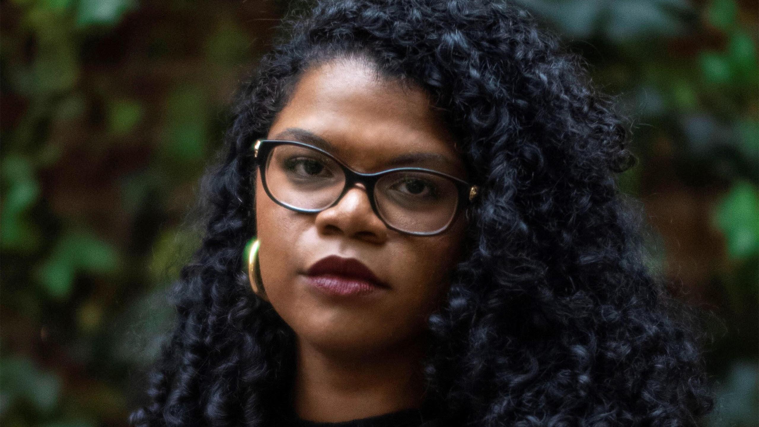 Black woman with long hair and glasses.