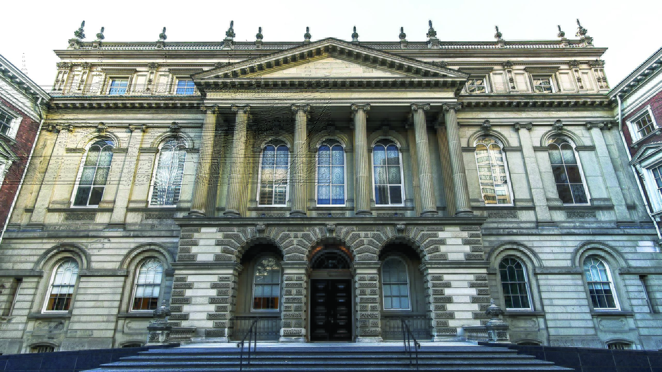 An image of Osgoode Hall in Toronto, a historic building design in the l late Palladian style. The building it two and a half stories, symmetrical and features stone pillars on the second story. The windows are tall with semi circles at the top. There are three stone arches at the entrance and pointy spires at the top of the building.
