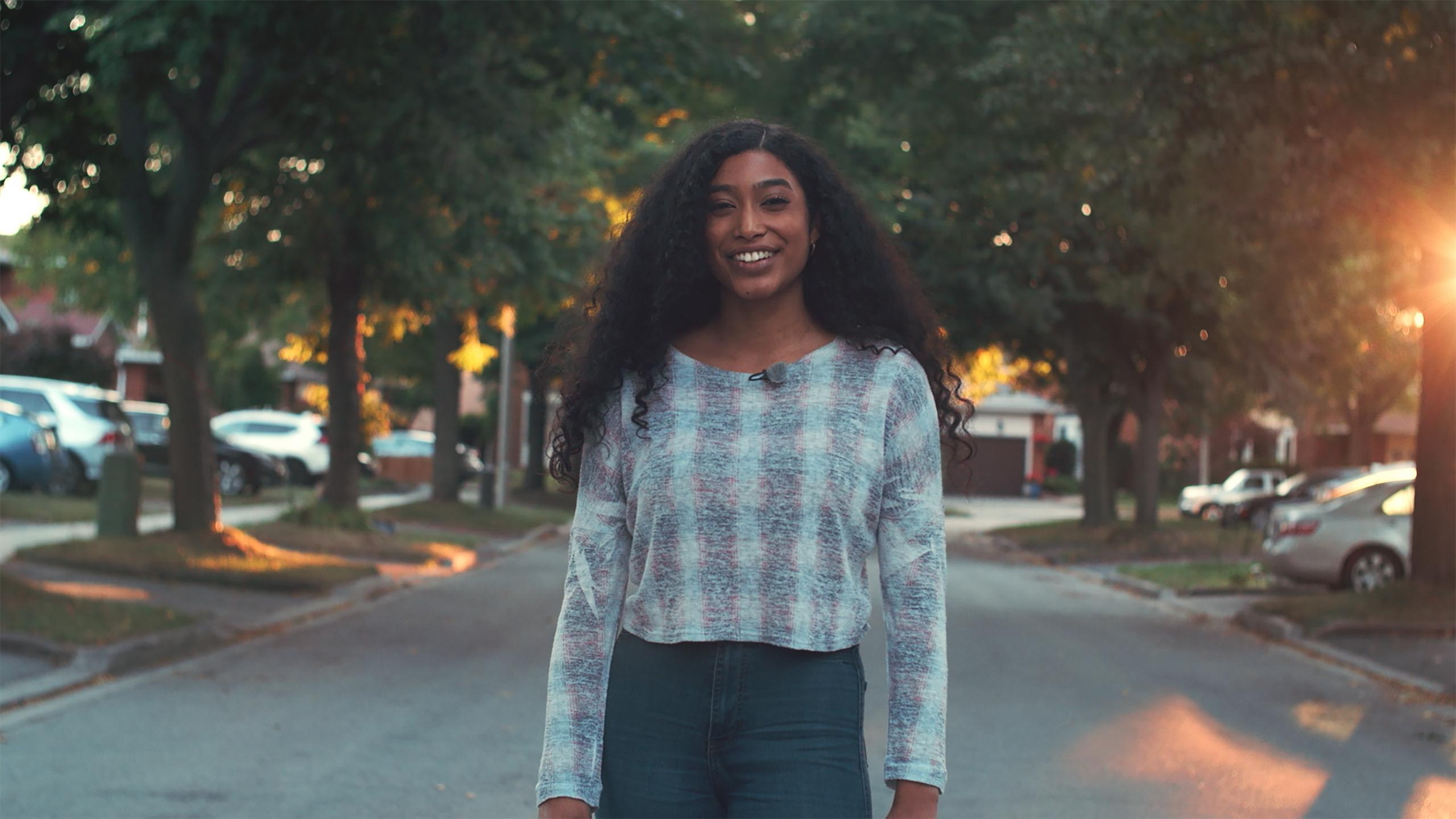 A photo of Naja Stanford standing in the street smiling at the camera.