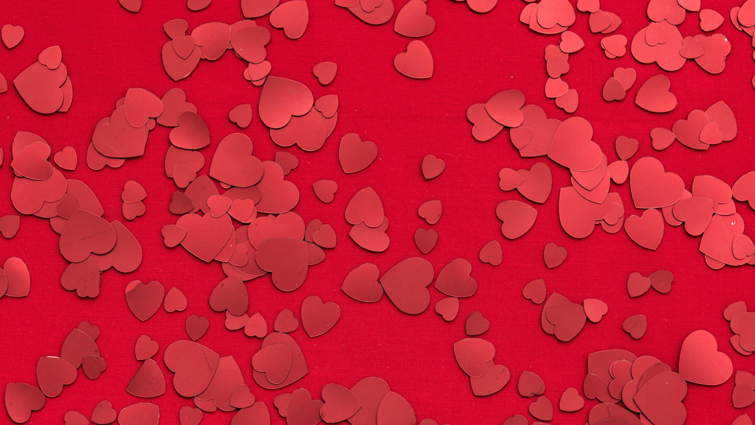 Red heart sequins scattered on a red background
