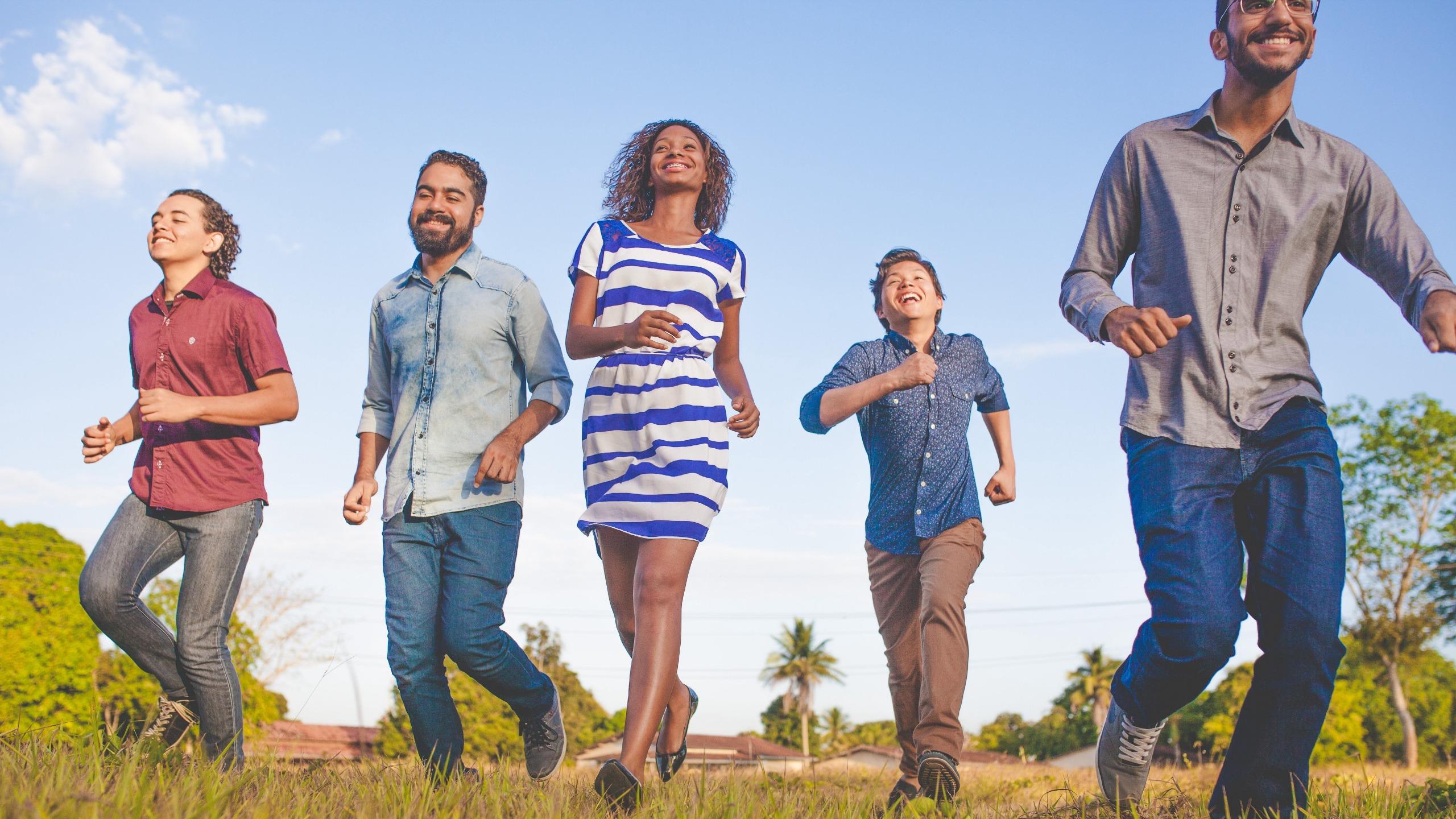 Group of friends running happily in a field