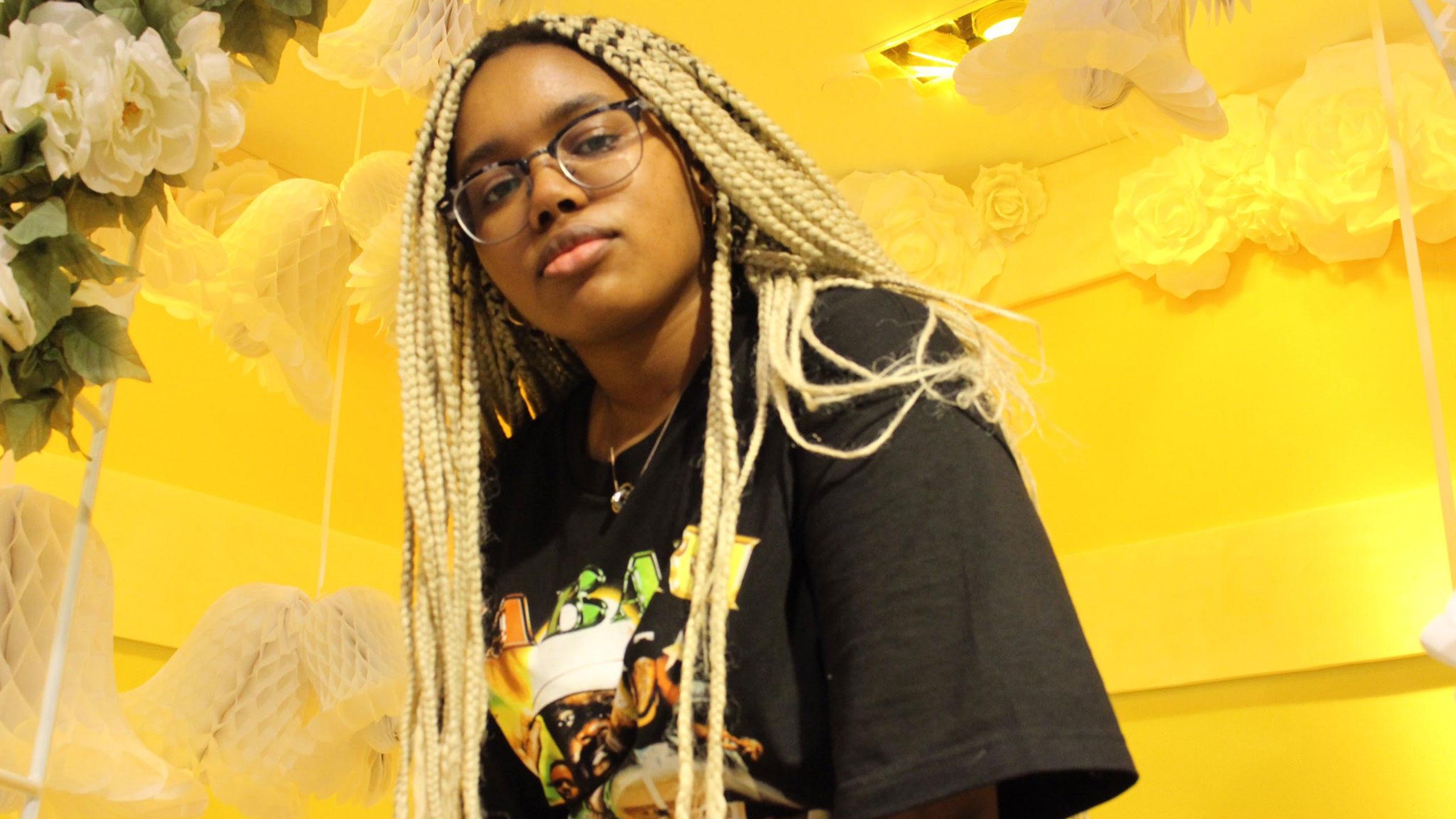 Adele Lukusa posing in front of a yellow background.