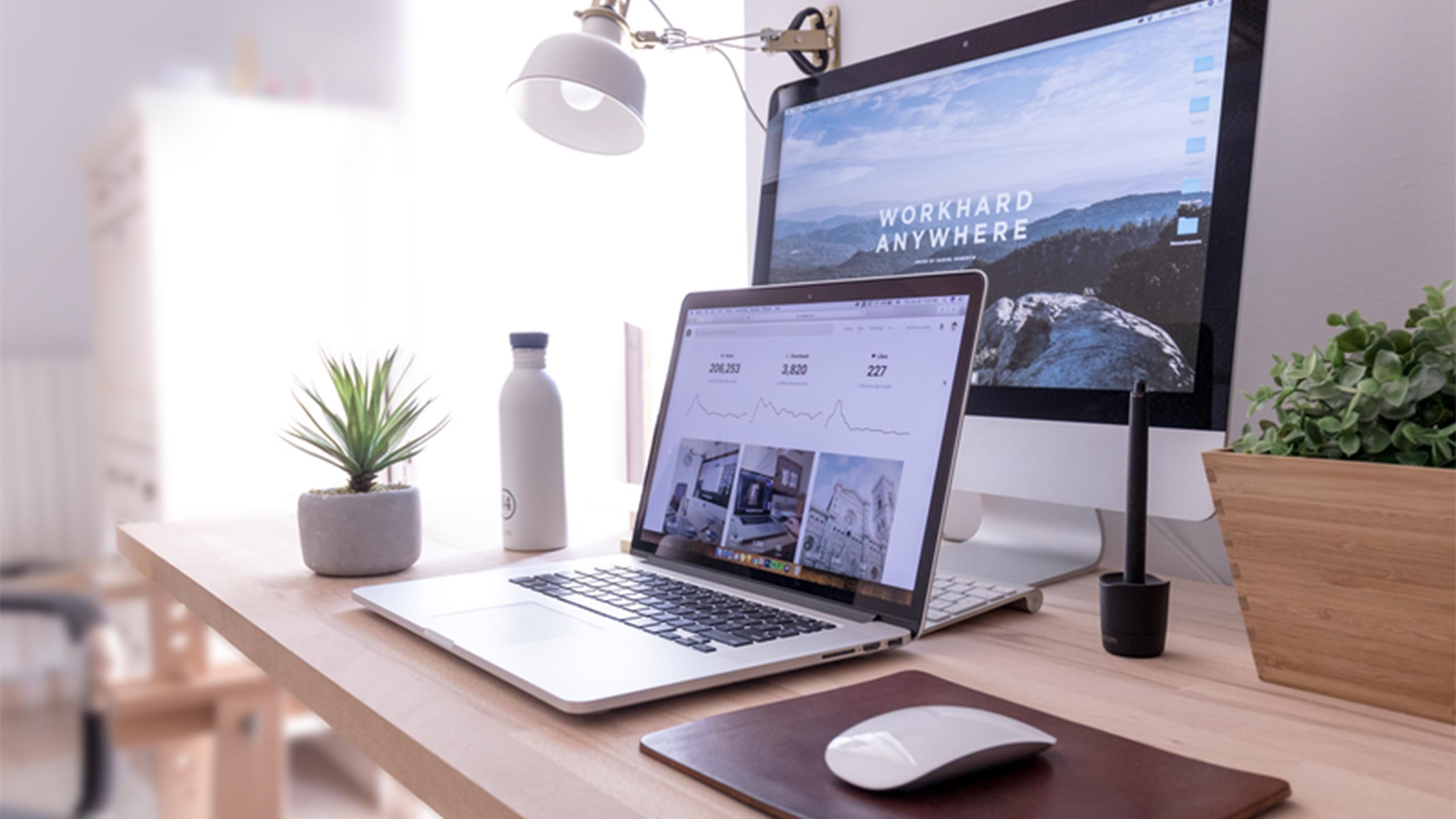 An organized home desk with natural light shining on it.