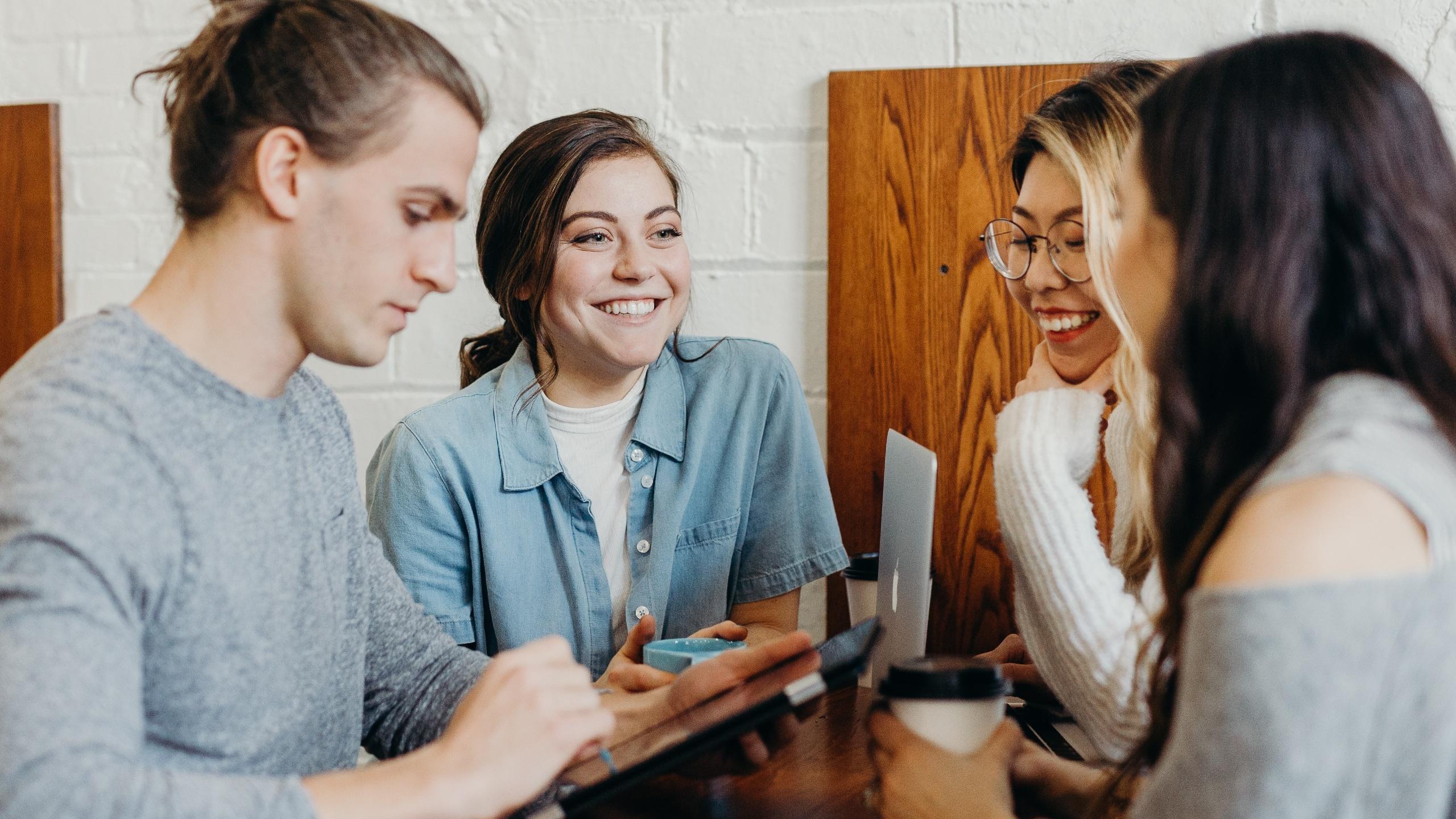 Three women and a man chatting at a table