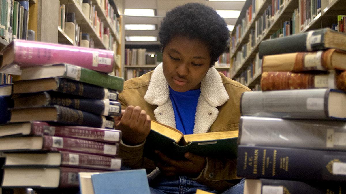 someone surrounded by piles of books reading a book