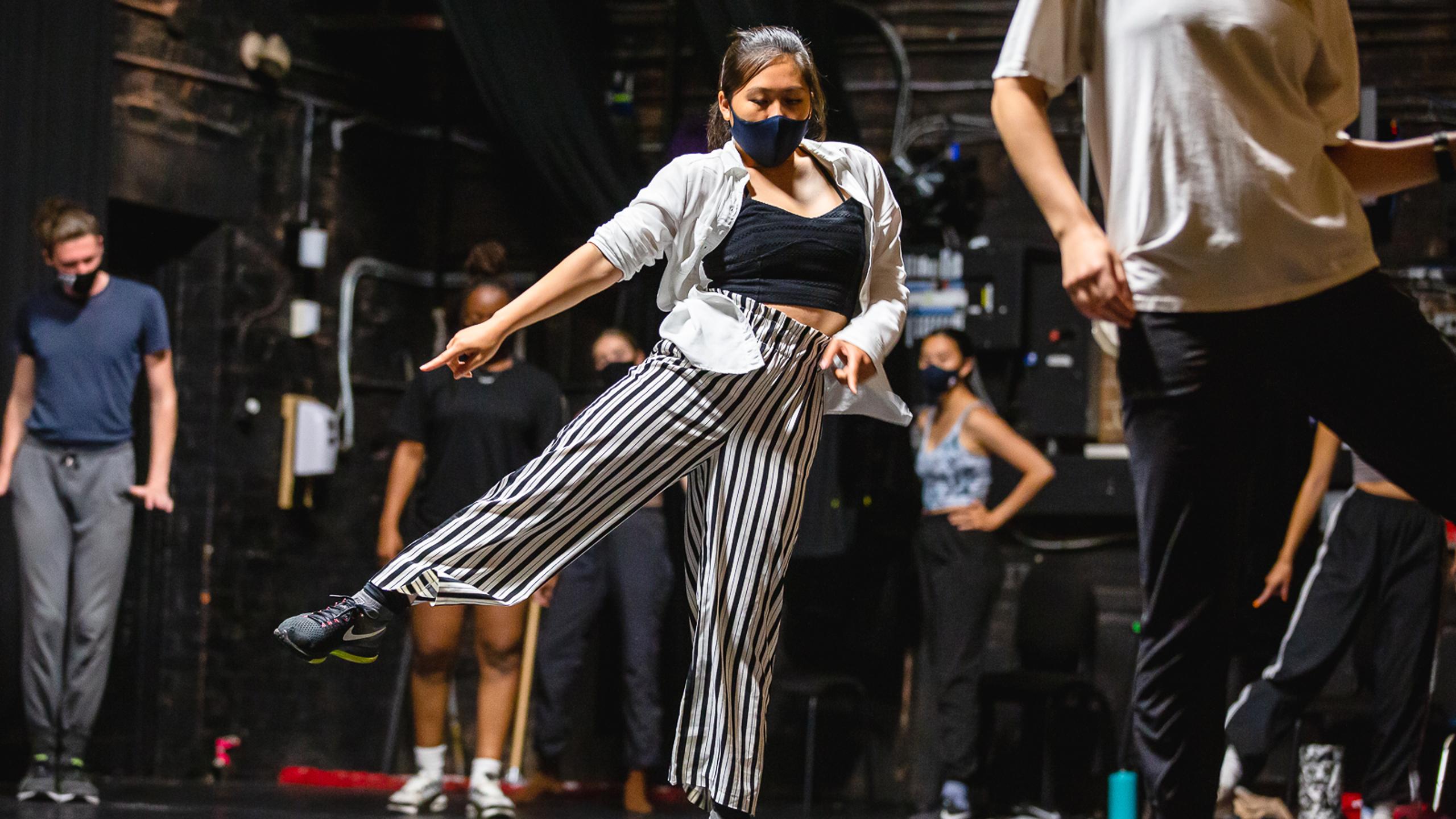 Woman with arm and leg out with people standing in the background