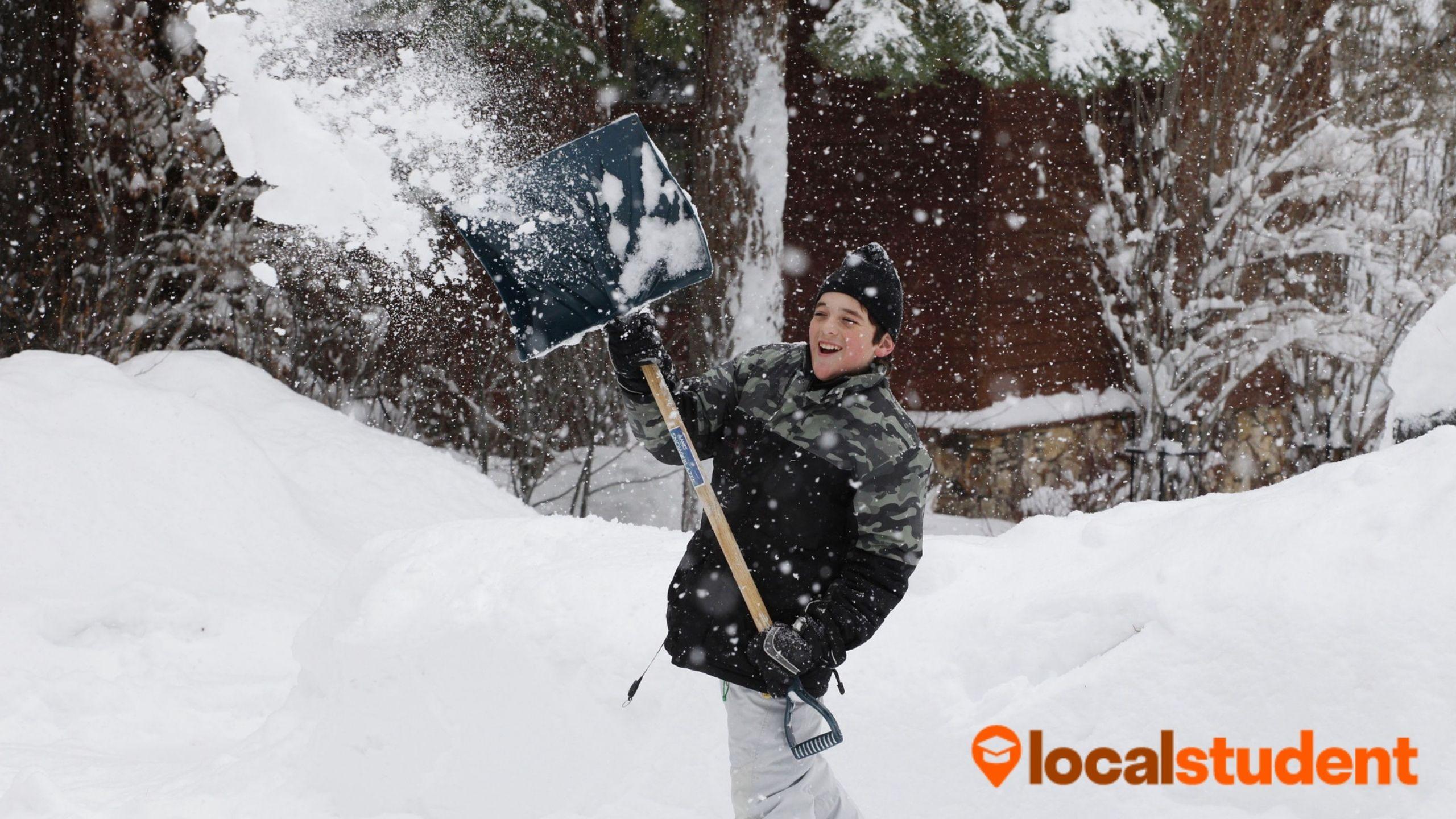 A teen throwing snow in the air using their shovel.
