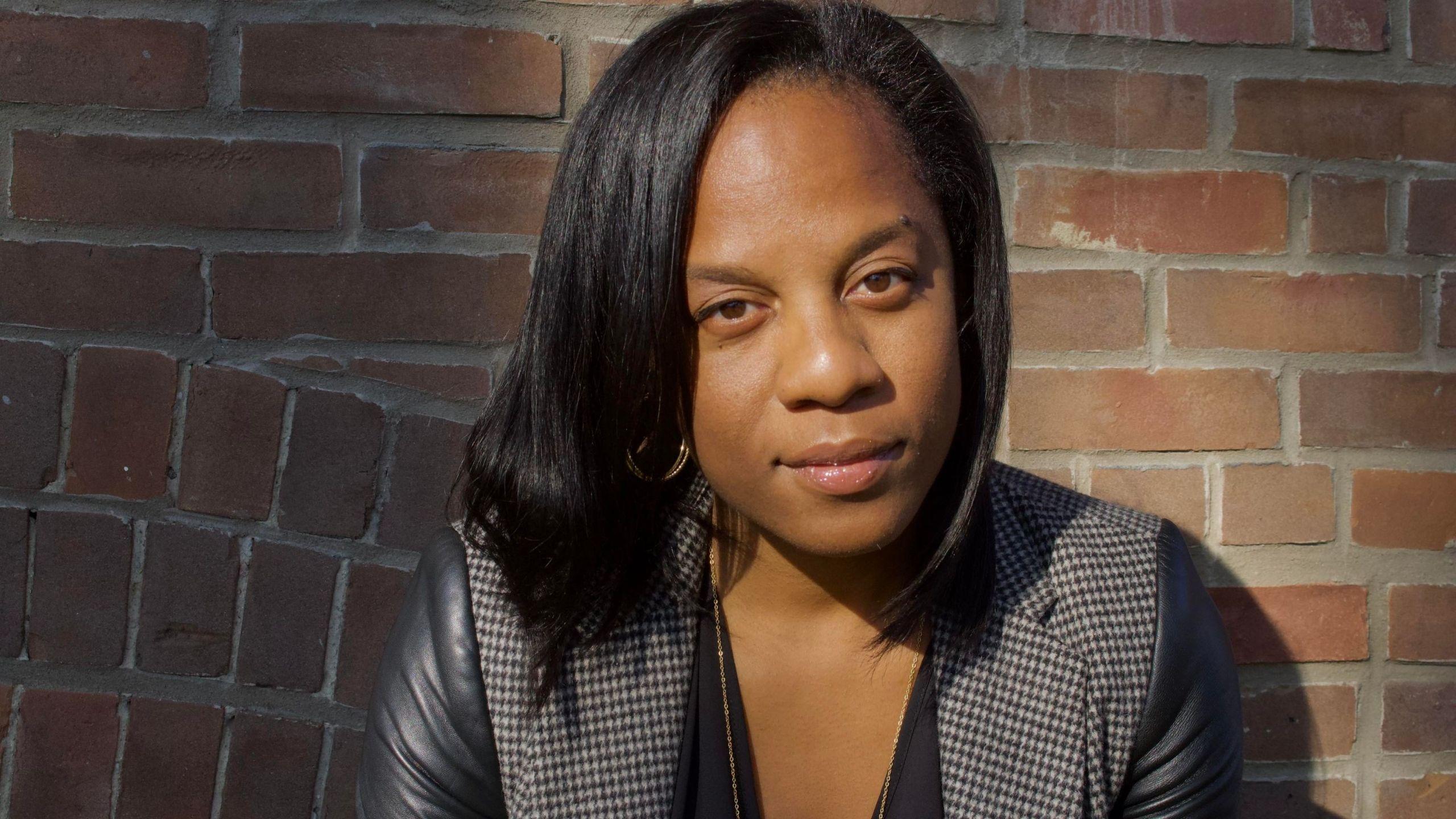 Headshot of Natalie Royer with a brick wall as background