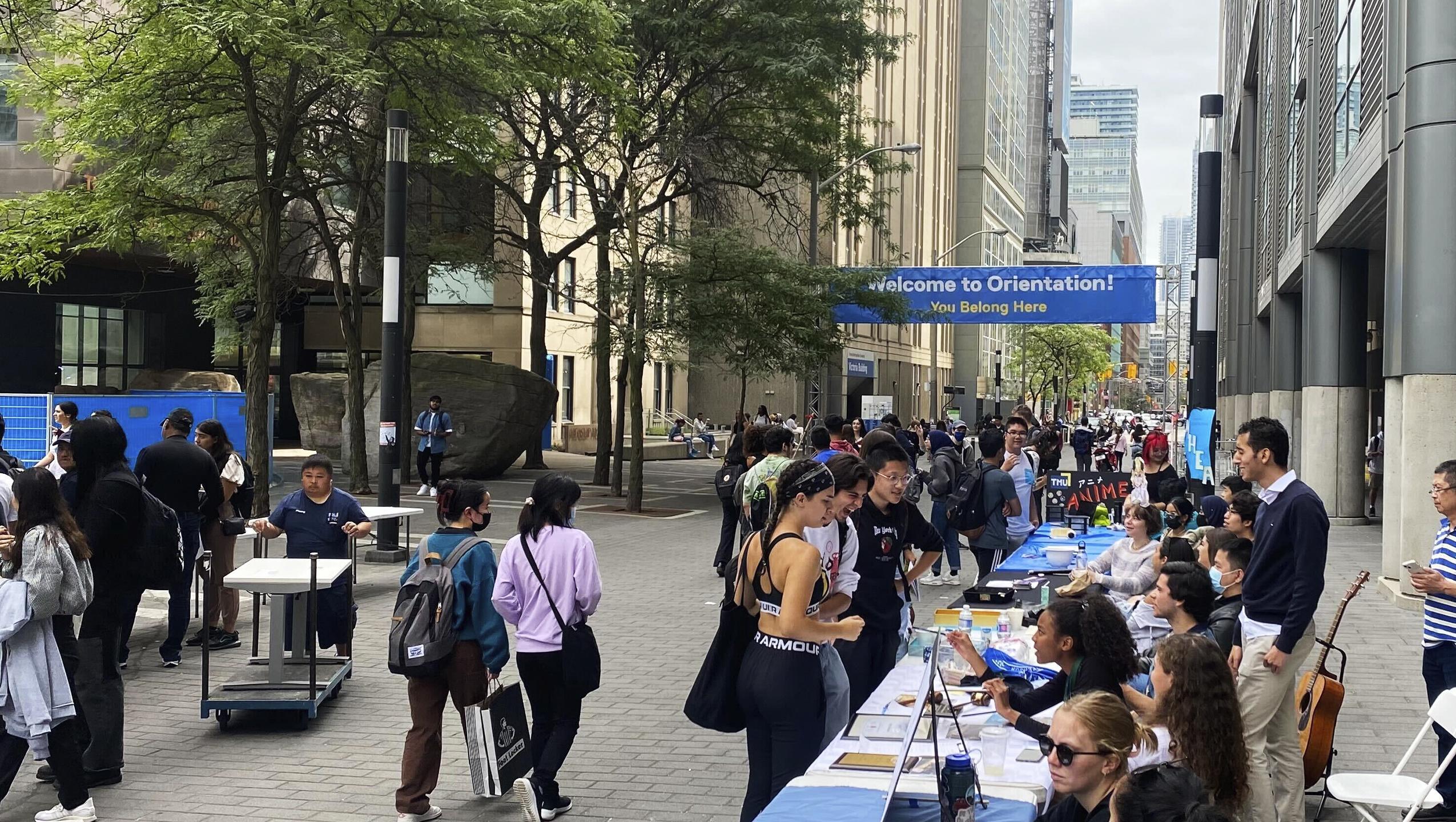 A overarching sign with the words "welcome to orientation, you belong here" with students walking underneath