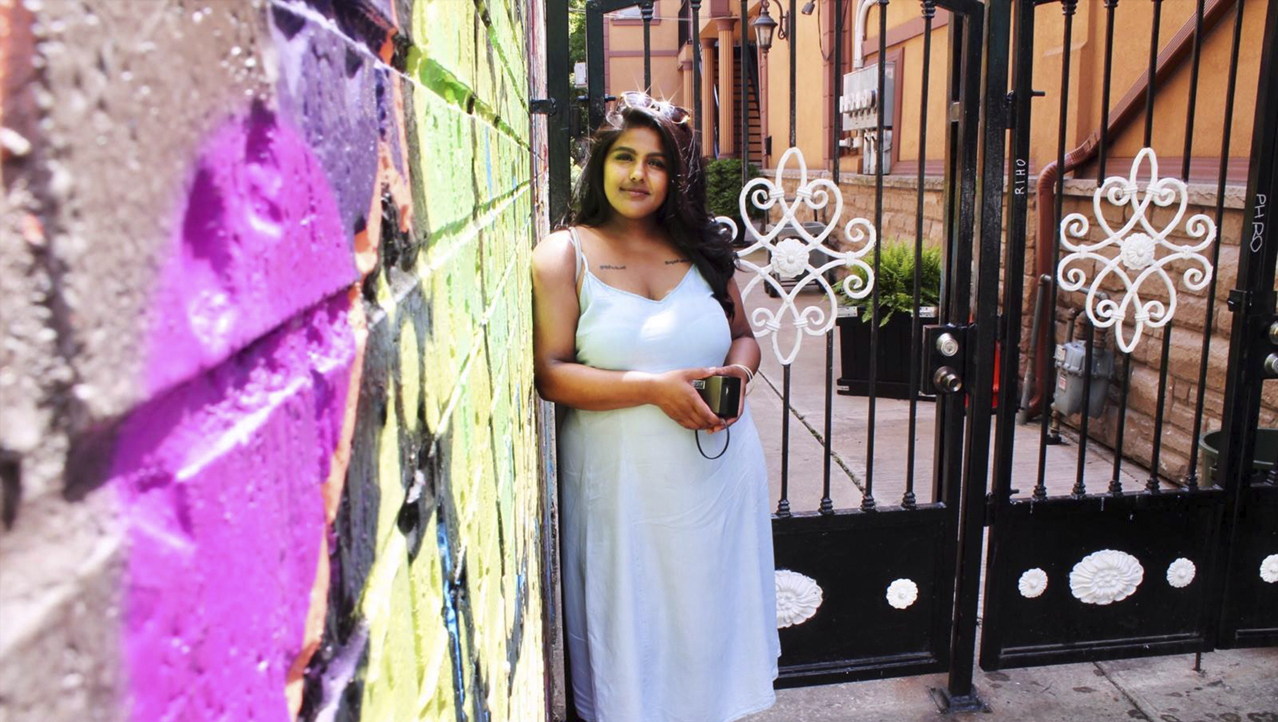 headshot of filmmaker Nayani leaning against a colourful brick wall