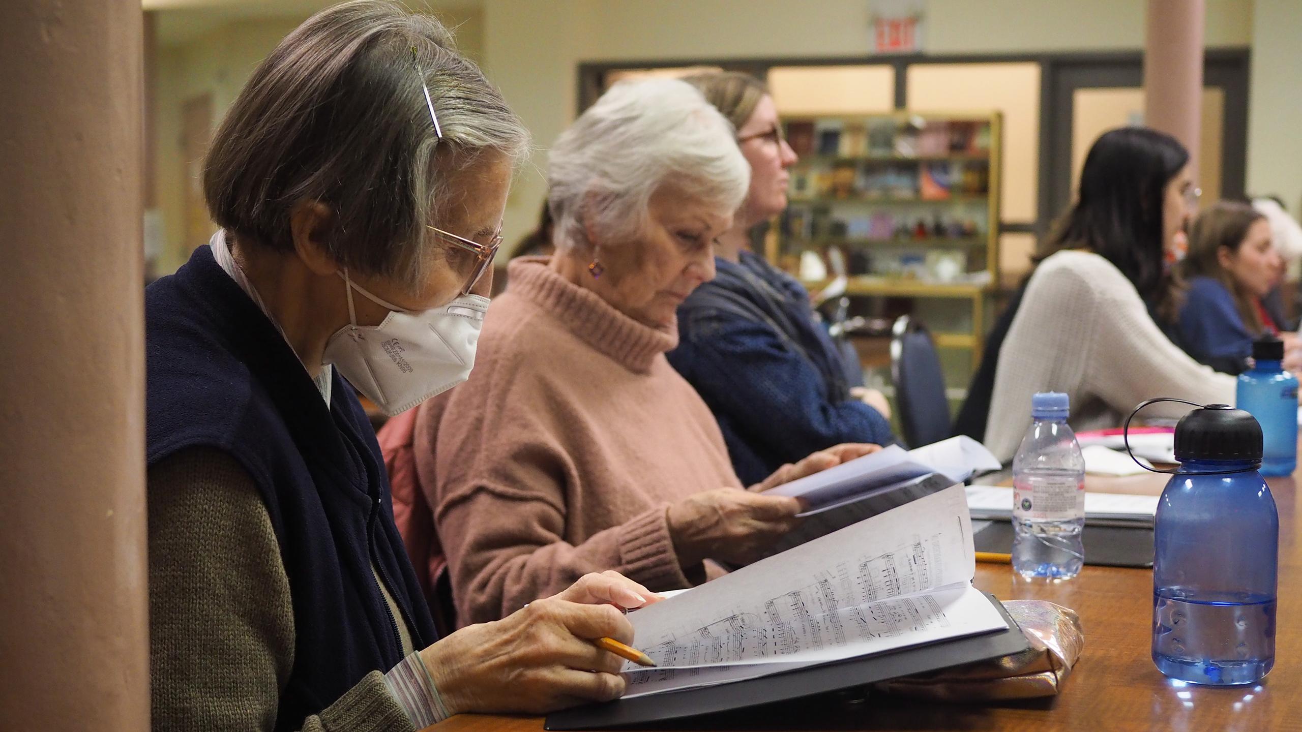 Members of the Toronto Concert Choir sitting around a table during their rehearsal.