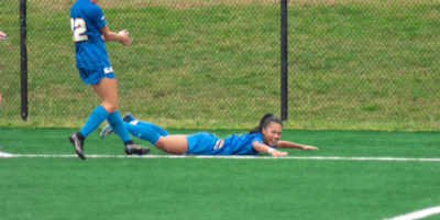 Ivymae Perez slides along the grass in celebration after scoring a goal.