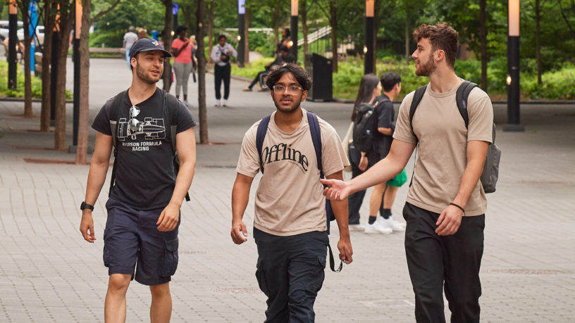 Three Students walk and talk outside Toronto Metropolitan University (TMU).