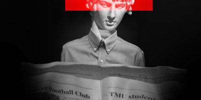 Statue with red bar across eyes wearing dress shirt reads newspaper