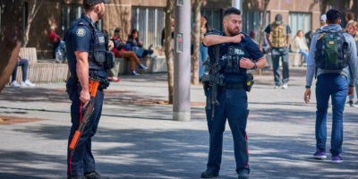 two police officers look around as they stand outside Toronto Metropolitan University (TMU)