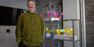 Portrait of artist standing next to their artwork