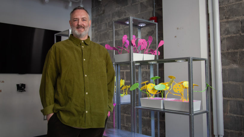 Portrait of artist standing next to their artwork