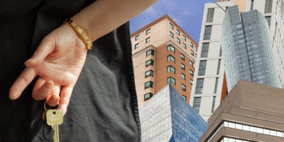 A hand dangles keys in front of a collage of Toronto buildings