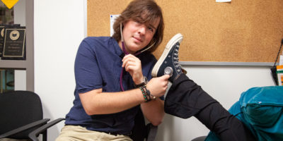 Man sitting on a chair holding a stethoscope to a woman's shoe