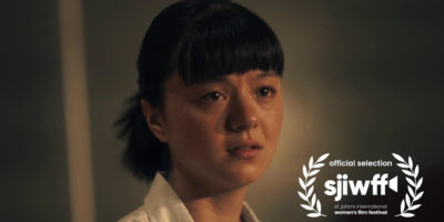 Still of the film "Poster Child" where a woman stands with tears in her eyes