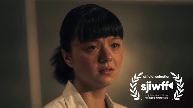 Still of the film "Poster Child" where a woman stands with tears in her eyes