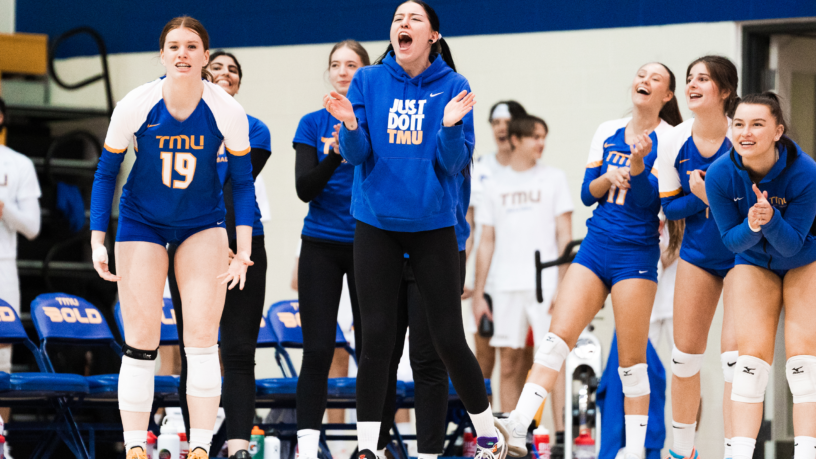 Members of the TMU Bold women's volleyball team celebrate on the bench