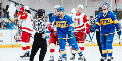 TMU men's player Kevin Gursoy points to bench while skating toward them after scoring goal