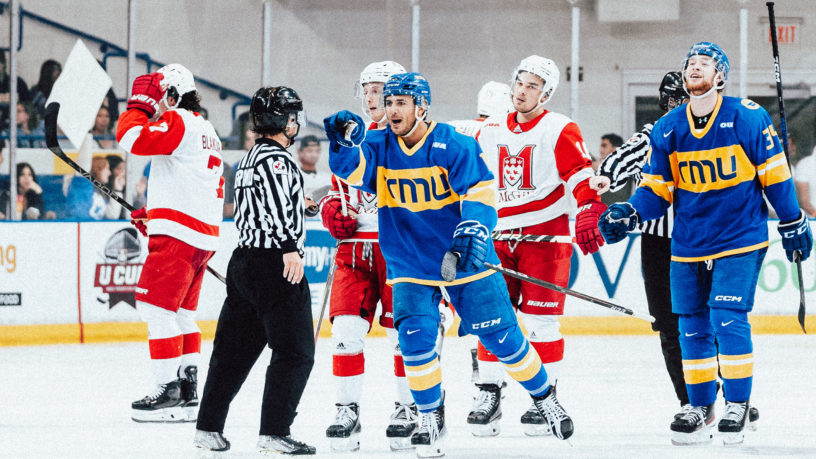 TMU men's player Kevin Gursoy points to bench while skating toward them after scoring goal