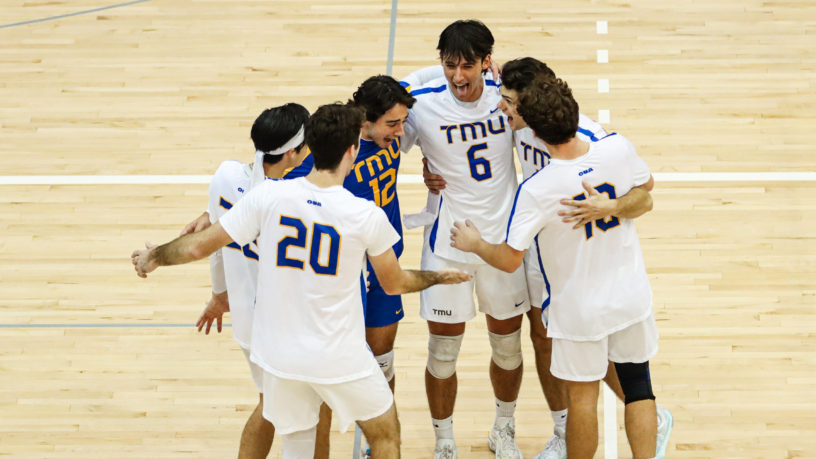 Players of the TMU men's volleyball team huddle in celebration of a win