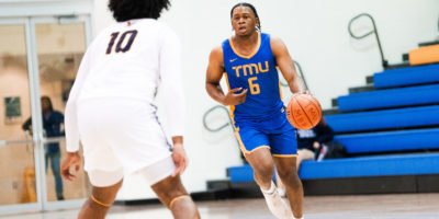 TMU men's basketball player David Walker dribbles the ball up the court