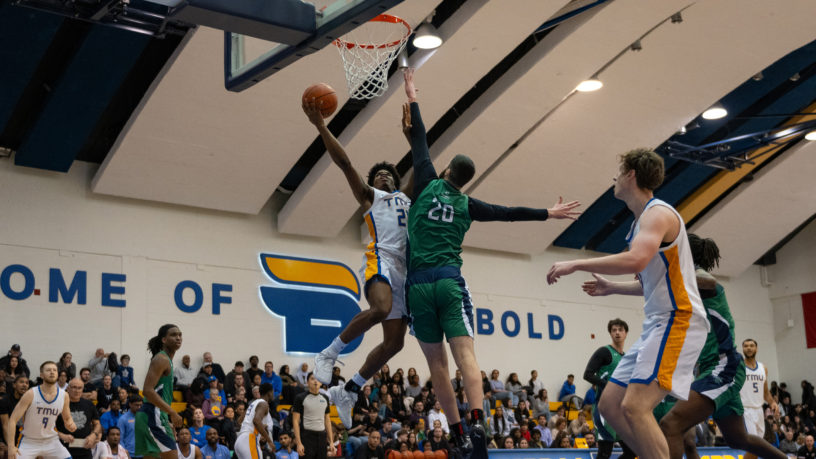 TMU men's basketball player Gabe Gutsmore goes up for a layup against a Nipissing defender