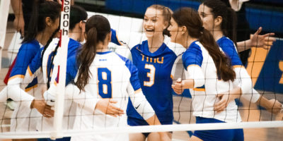 TMU women's volleyball players celebrate on the court after a point