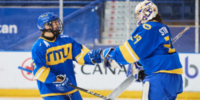 TMU women's hockey players Tori Butler and Alexia Stratos pat gloves after a win