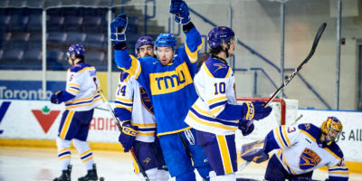 TMU men's ice hockey player Connor Bowie celebrates a goal in front of four Golden Hawks players