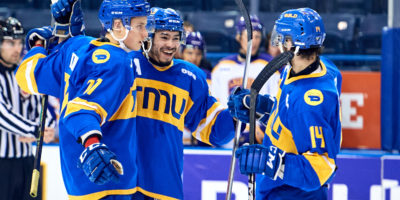 TMU men's hockey players Kyle Bollers, Artem Duda and Chris Playfair hug after a goal