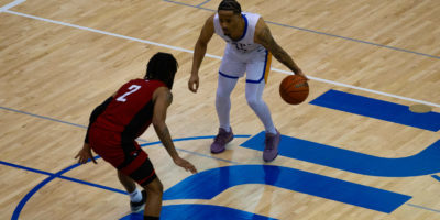 TMU Bold men's basketball player Cameron Ramage brings the ball to half court as a York defender is close to him