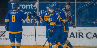 TMU Bold men's hockey players give each other fist bumps on the ice