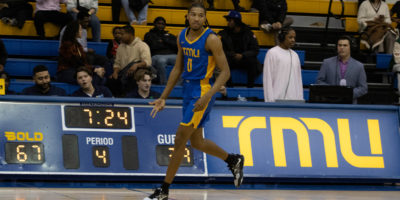 TMU Bold men's basketball player Adrian Stevens holds three fingers to the ground