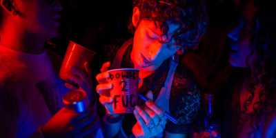 Three people holding drinks lit up with pink lights