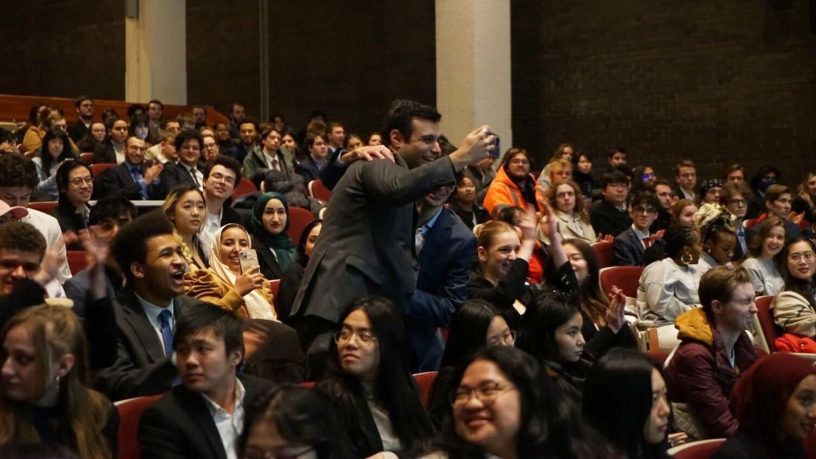 people standing in a crows of people sitting and cheering