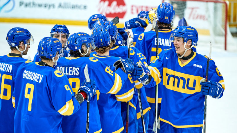 The TMU men's hockey team fist bump each other while skating on the ice in celebration of a win