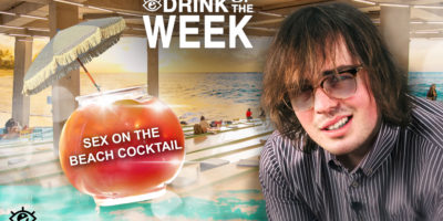 a man with sunglasses staring confused into the camera to the right, to the left a pink and red drink with an umbrella coming out of the top