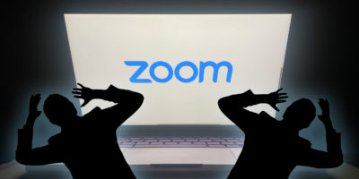 two silhouettes of people scared of a bright screen that has the blue zoom logo
