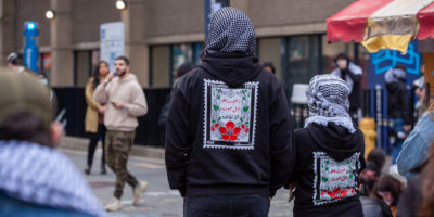 Demonstrators wearing cultural clothing listening to a speaker at the sit-in