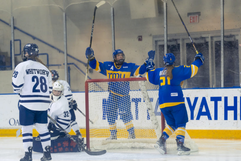 Emily Baxter and Megan Breen raise their arms and sticks to celebrate a goal against the Toronto Varsity Blues