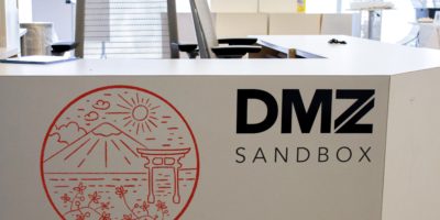 A photo illustration of the DMZ front desk stamped with an outlined image of Japan.