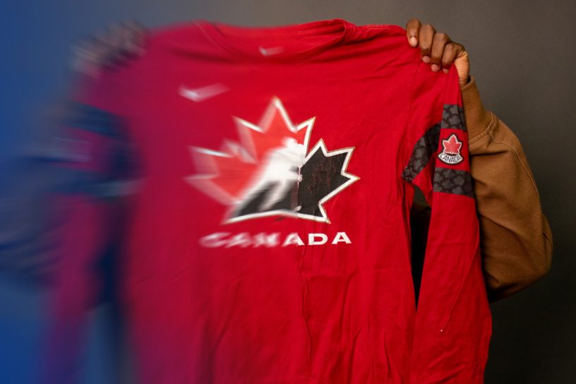 A photo of someone holding up a partially blurred Canada hockey shirt.