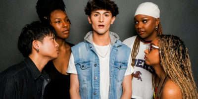 An image of multiple individuals staring at the person standing in the centre of the photo