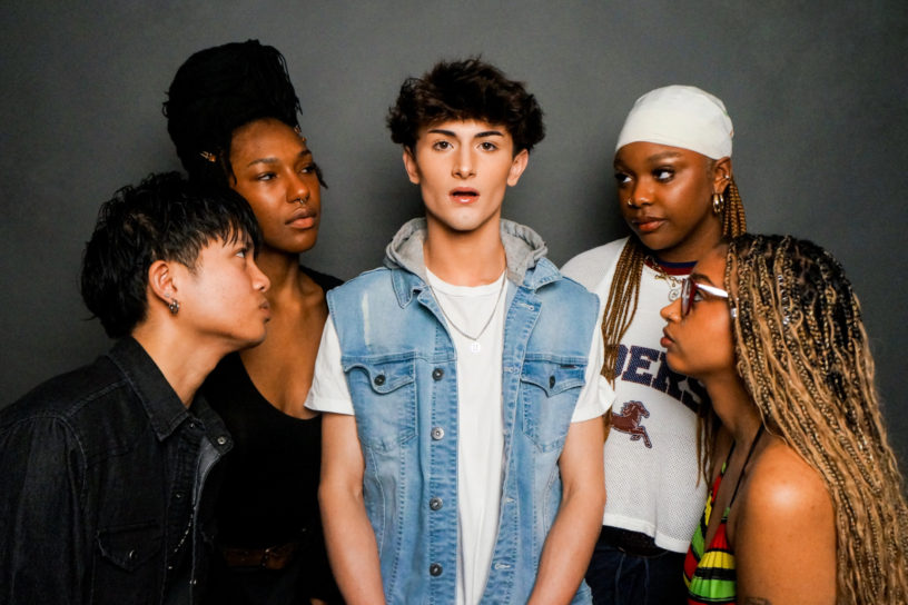 An image of multiple individuals staring at the person standing in the centre of the photo